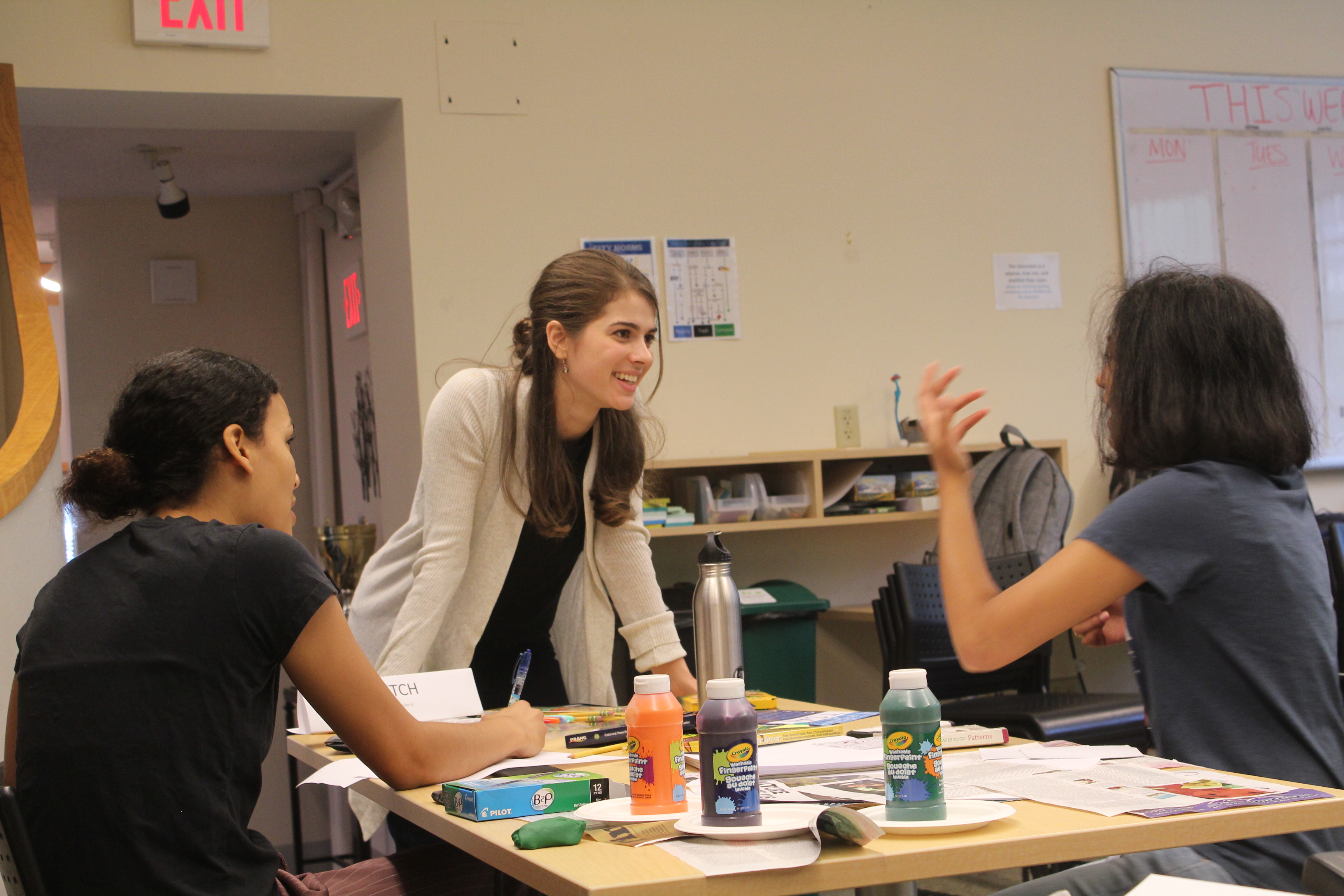 Three students work with art supplies